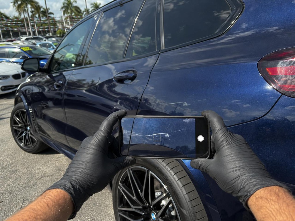 Inspector photographing a scratch on a blue BMW X5 for the inspection report