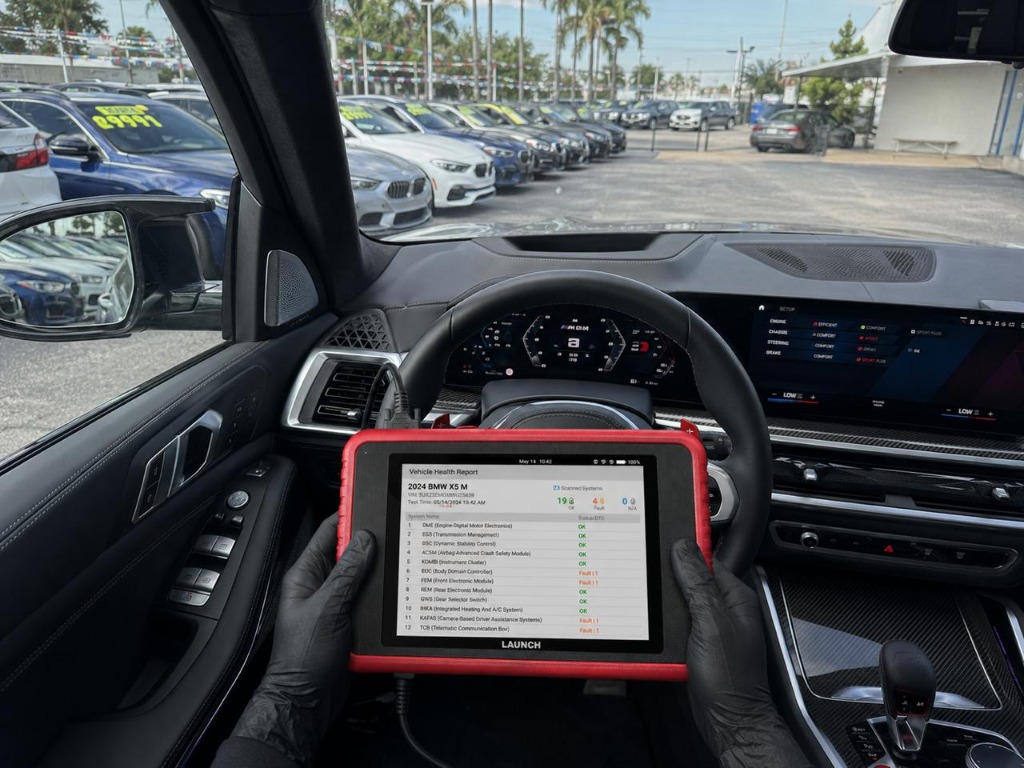 Inspector running diagnostics on a BMW X5 M — LAUNCH scanner showing vehicle health report
